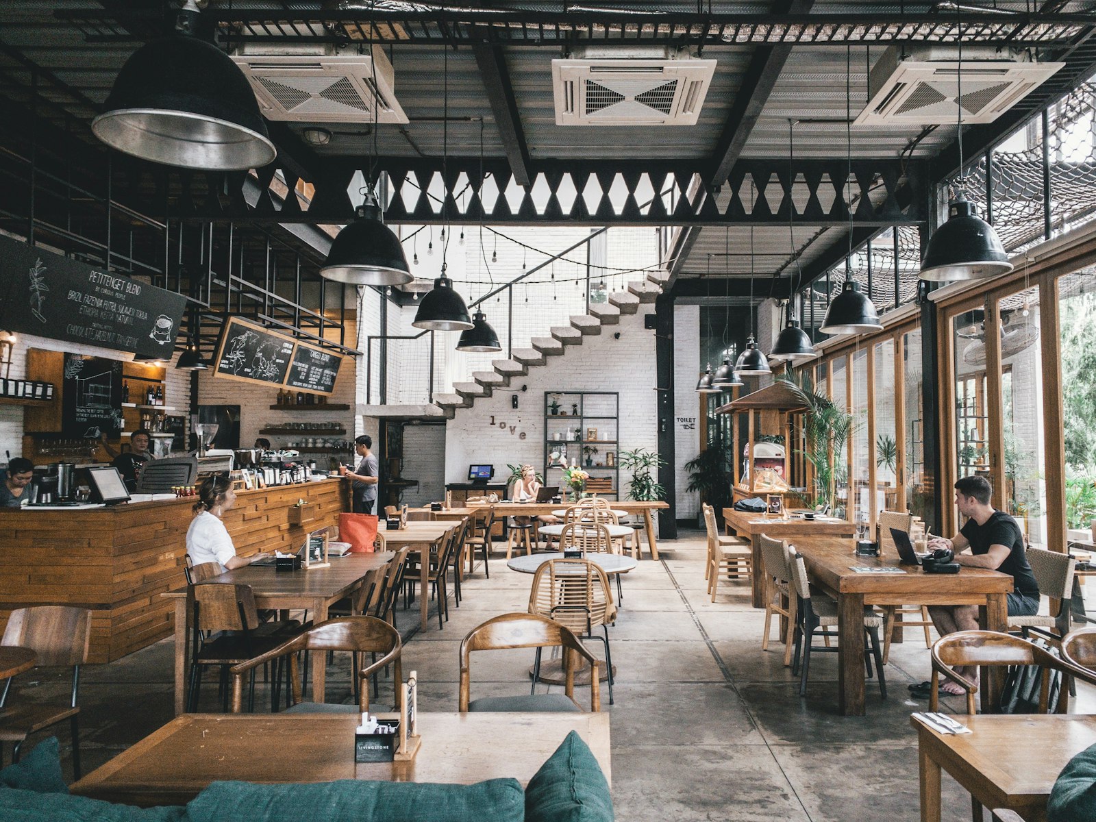 Warm ambient Italian trattoria dining room with wine glasses and wood-fired pizza